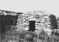Cabane à l'entrée couverte par un linteau surmonté d'un arceau; mur avec niche à gauche © Elie Malé